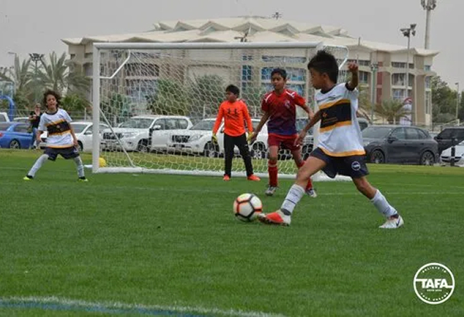 A lively scene of young boys playing soccer on a field, demonstrating skill and camaraderie during their game