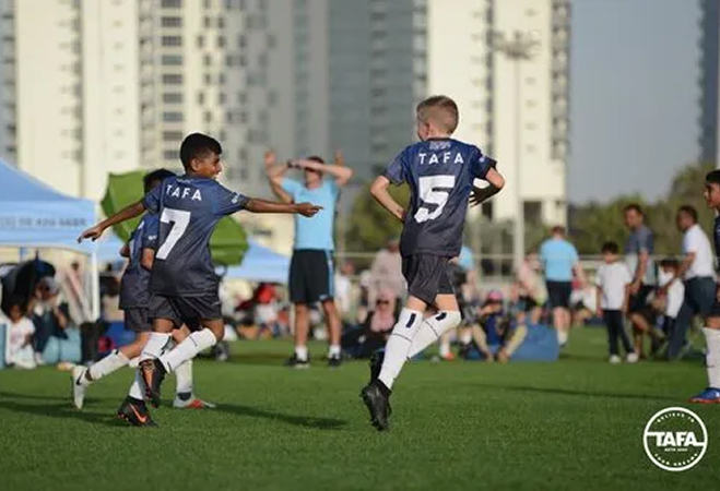 Several young boys engaged in a soccer game on a vibrant green field, showcasing teamwork and enthusiasm